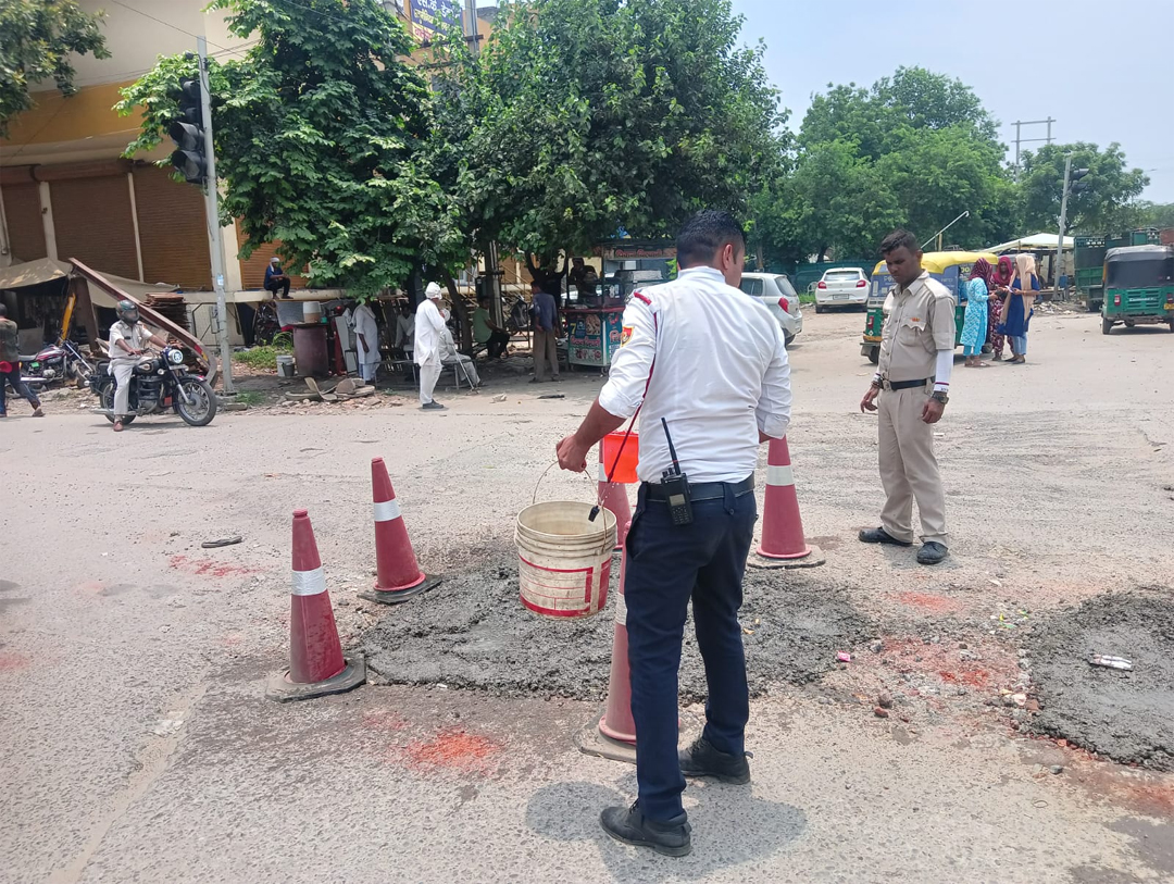 फरीदाबाद ट्रैफिक पुलिस अपनी ड्यूटी भी कर रही है और सड़क के गड्ढे भी भर रही है